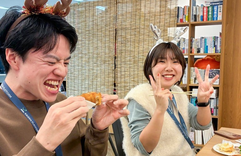 東京オフィスでの忘年会の一場面の写真。トナカイのカチューシャを付けた2人のメンバーがチキンを食べたり、ピースサインをしている。