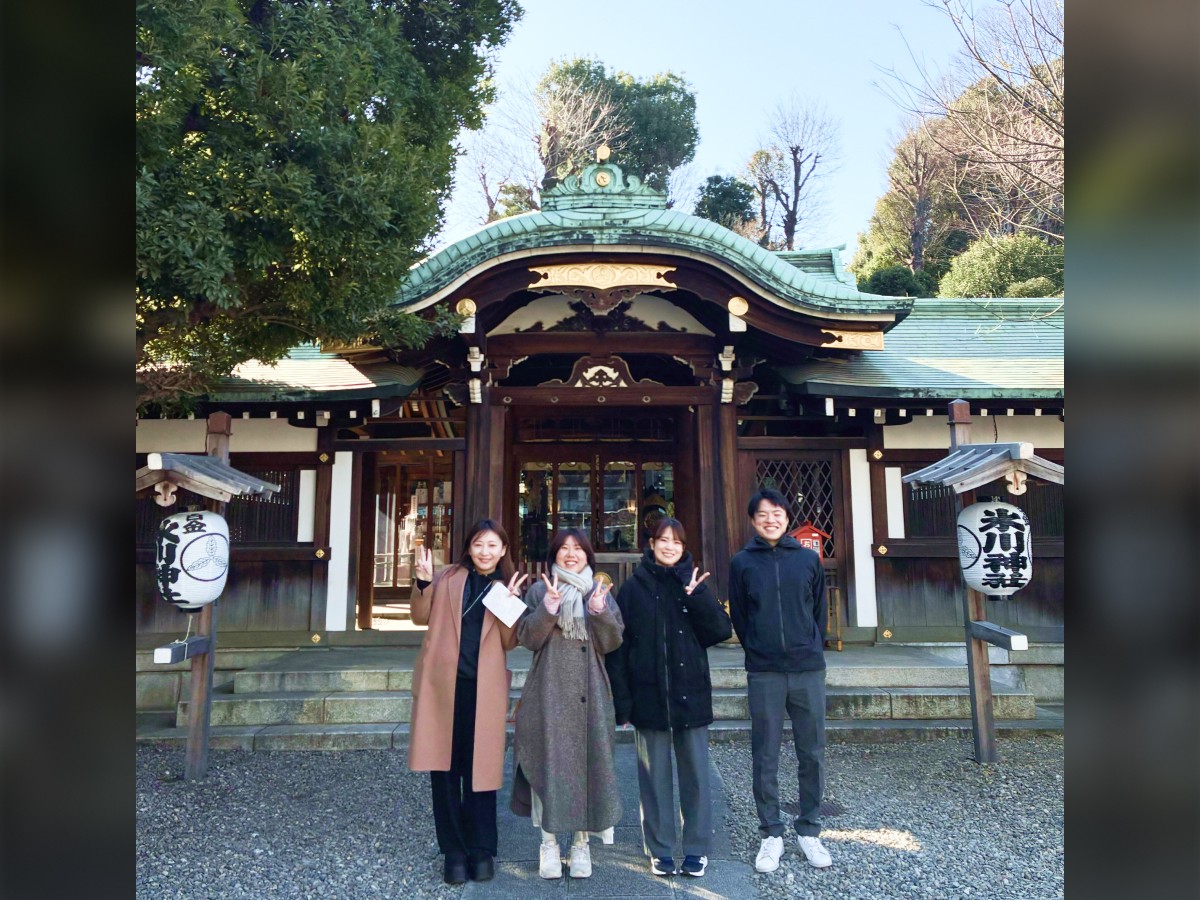 東京オフィスの初詣の様子。お社の前で、社員がピースサインをしたりしながら並んで立っている。